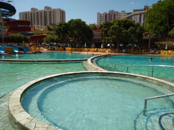 A pool area with multiple water slides and a clear view of surrounding buildings.
