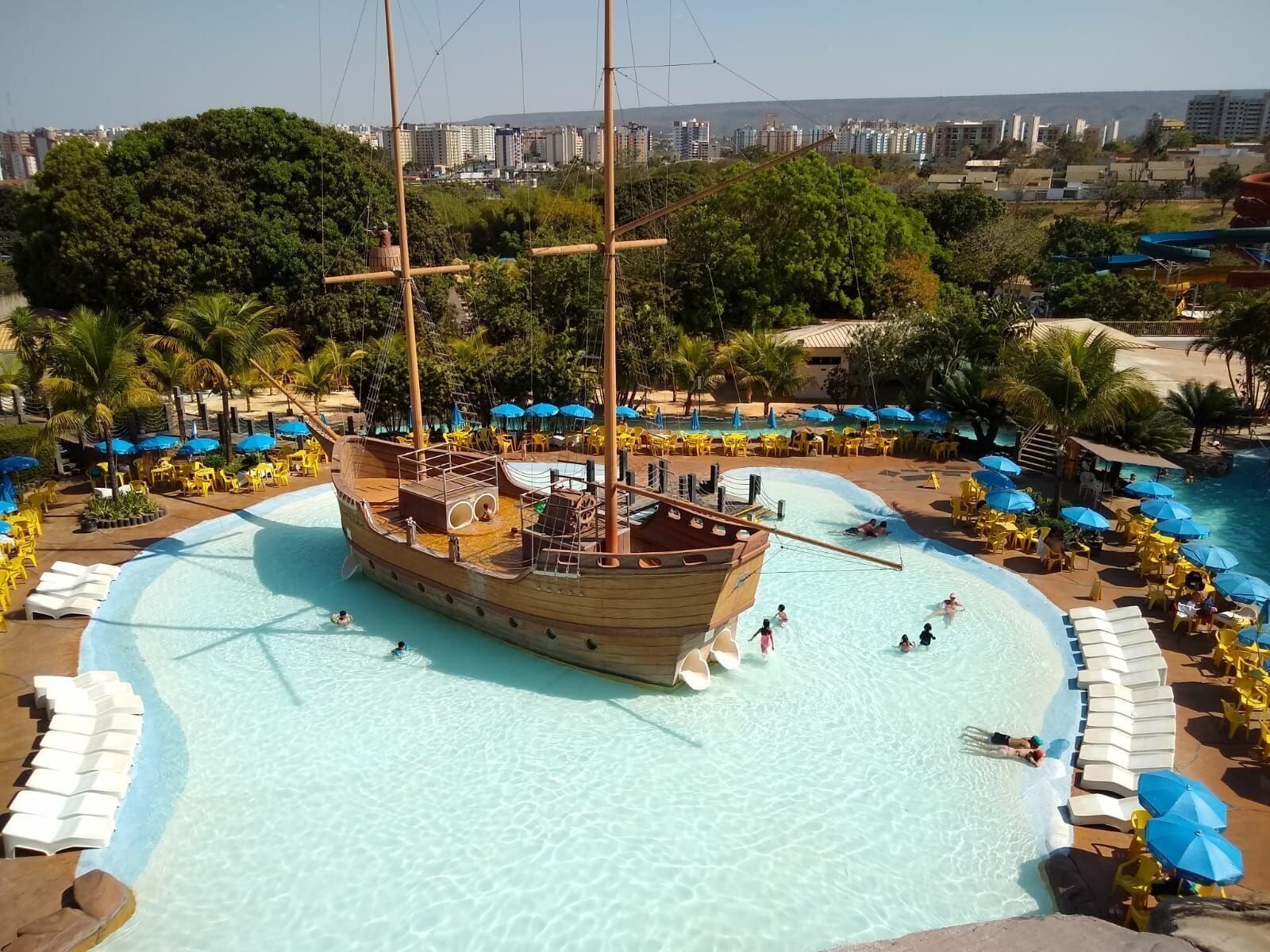 A pirate ship-shaped pool with lounge chairs and umbrellas around it.