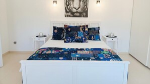 Une chambre à coucher avec un lit blanc, une décoration murale sur le thème du tigre, des coussins à motifs et des tables de chevet avec des lampes.
