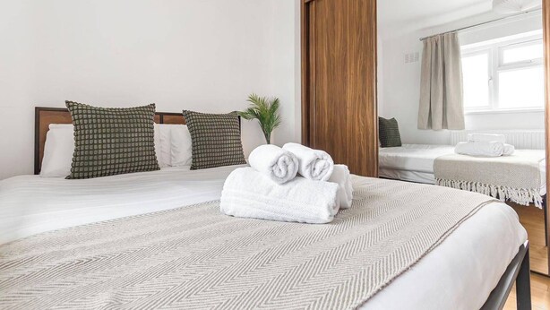 Ein Hotelzimmer mit zwei Betten, einem großen Spiegel und einer Topfpflanze.