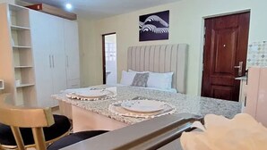 Een hotelkamer met een bed, een klein tafeltje met borden, een stoel en een kledingkast.