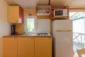 A compact kitchen with a sink, stove, microwave, and refrigerator.