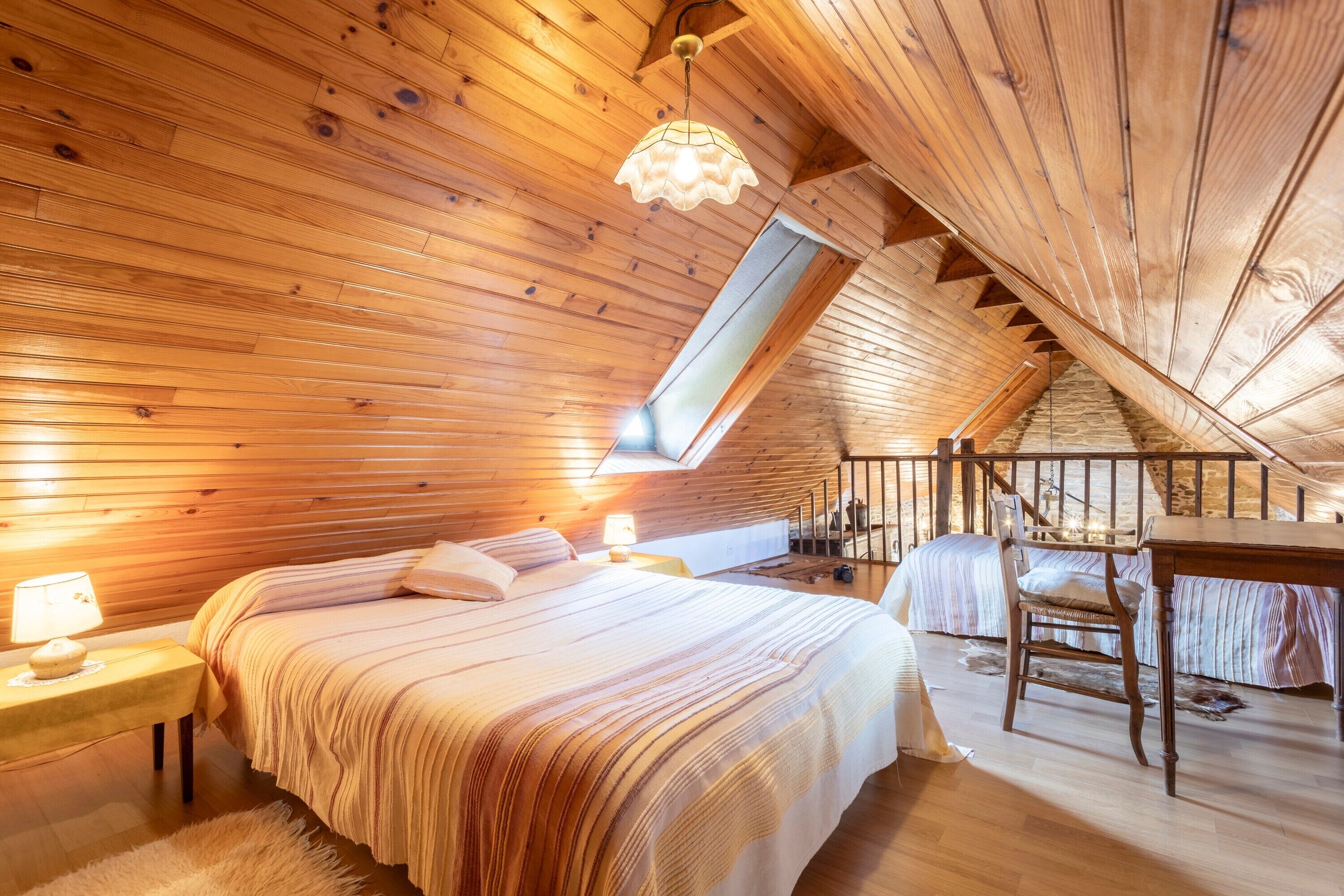 A cozy attic bedroom with a sloped ceiling, a bed, a desk, and a chair.