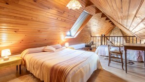 Um quarto de sótão acolhedor com teto inclinado, uma cama, uma escrivaninha e uma cadeira.