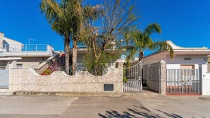 A gated residential property with a stone wall, a gate, and a staircase leading to a second floor.