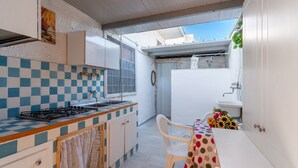 A compact kitchen with a gas stove, a sink, and a small dining area with a table and chairs.
