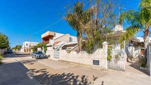 A residential street with houses, a car, and a gate.