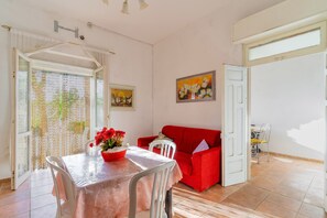 Un comedor con una mesa y sillas, un sofá rojo y un cuadro en la pared.