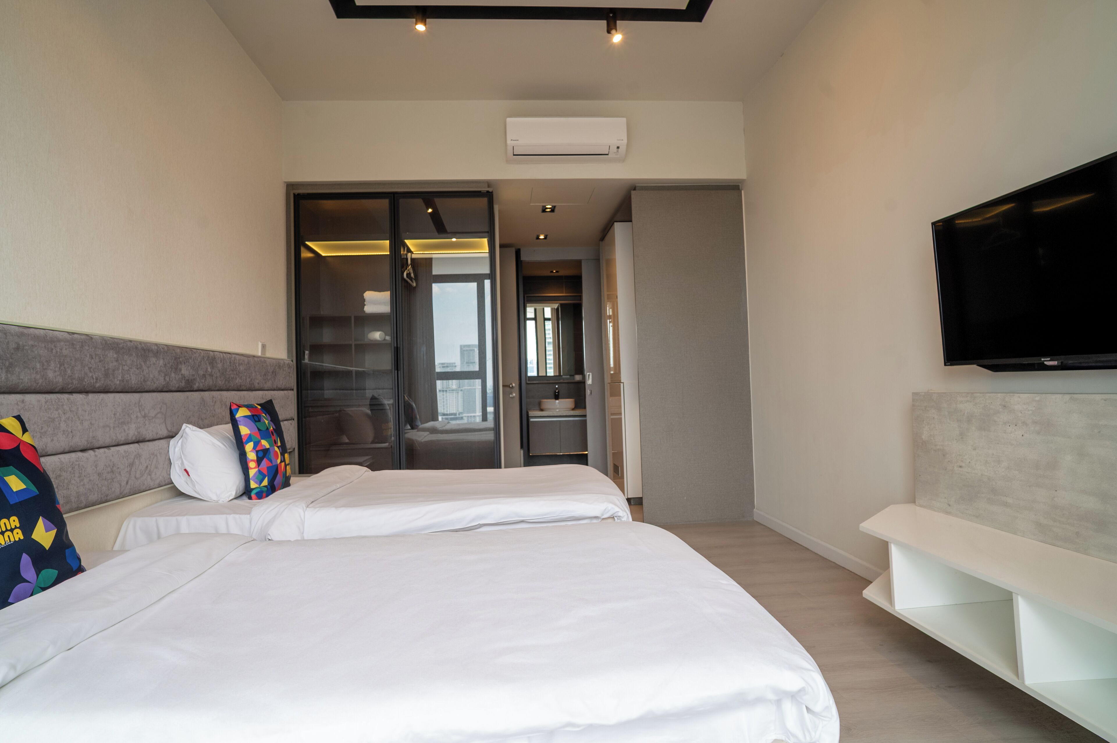 Una habitación de hotel moderna con una cama grande, un televisor montado en la pared y un vestidor.