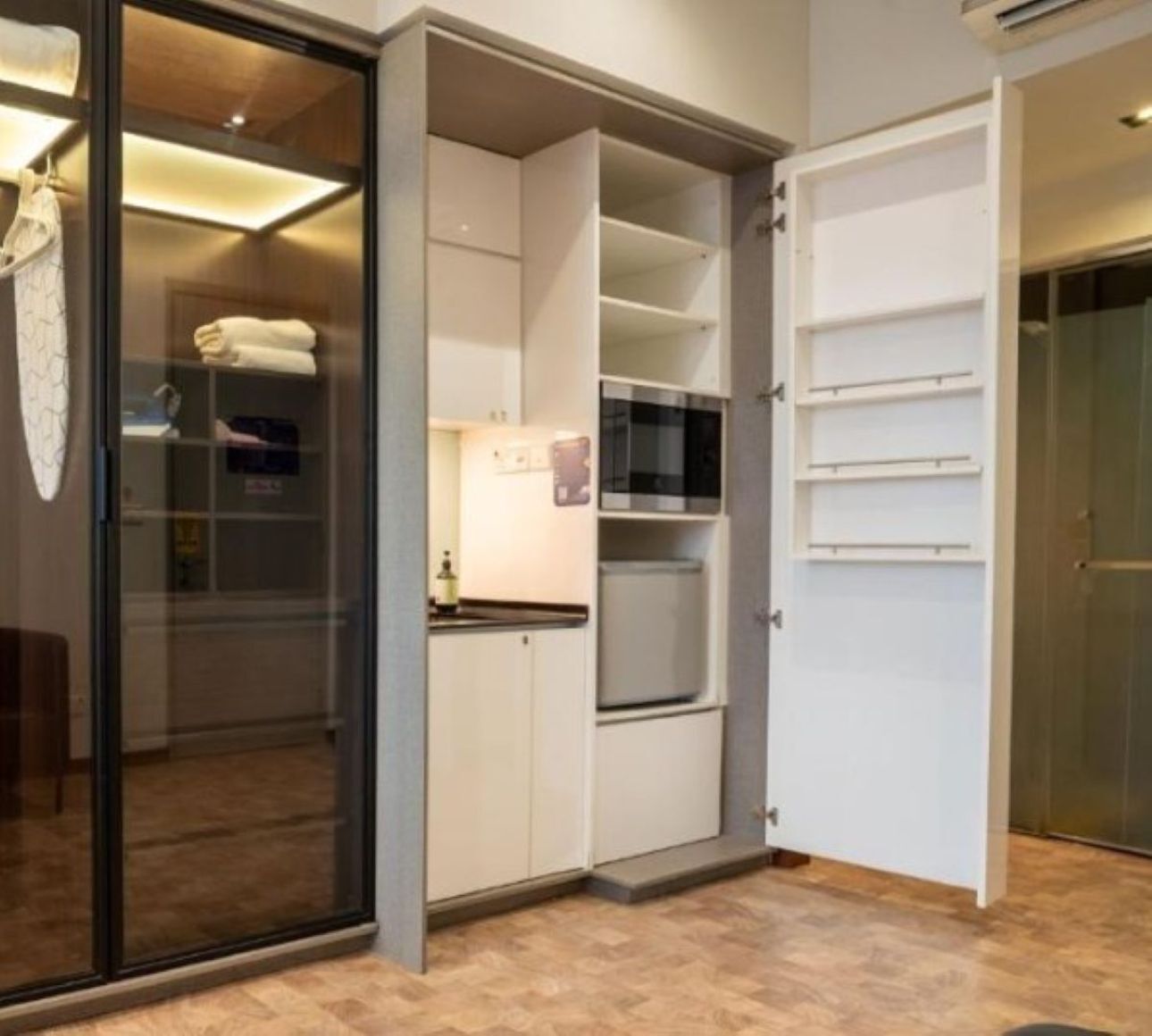 A modern kitchen with built-in appliances, a glass door pantry, and a white cabinetry layout.