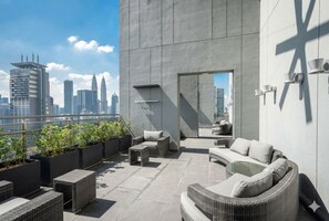 A rooftop terrace with outdoor furniture, a city skyline view, and a modern building facade. - EXPRESSIONZ KLCC BY MANA-MANA (Kuala Lumpur)