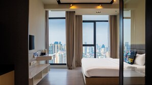 Ein modernes Hotelzimmer mit einem großen Bett, einem Fernseher, einem Nachttisch und Blick auf die Stadt.