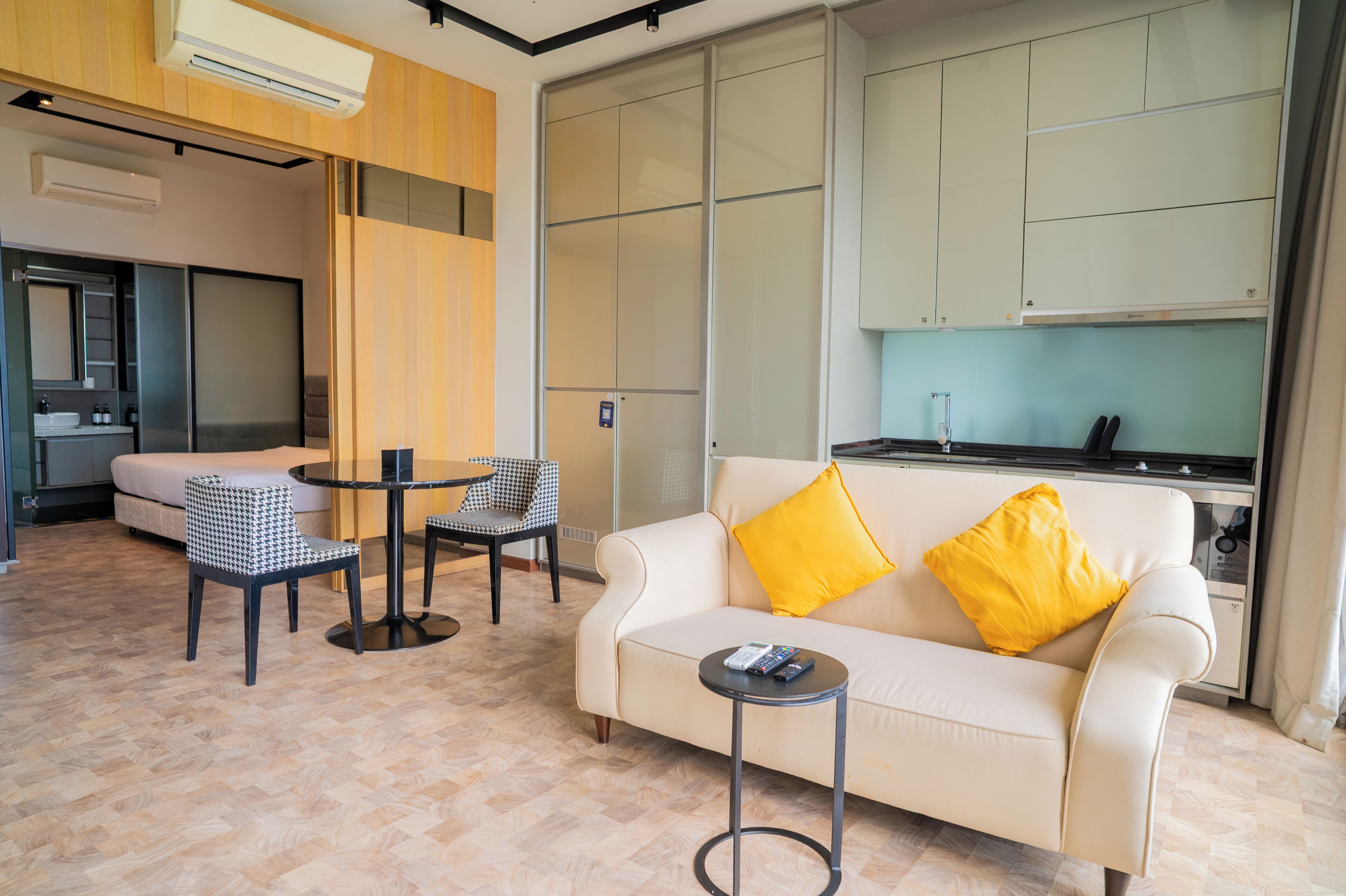 A modern living room with a sofa, two chairs, a small table, and a kitchen area in the background.