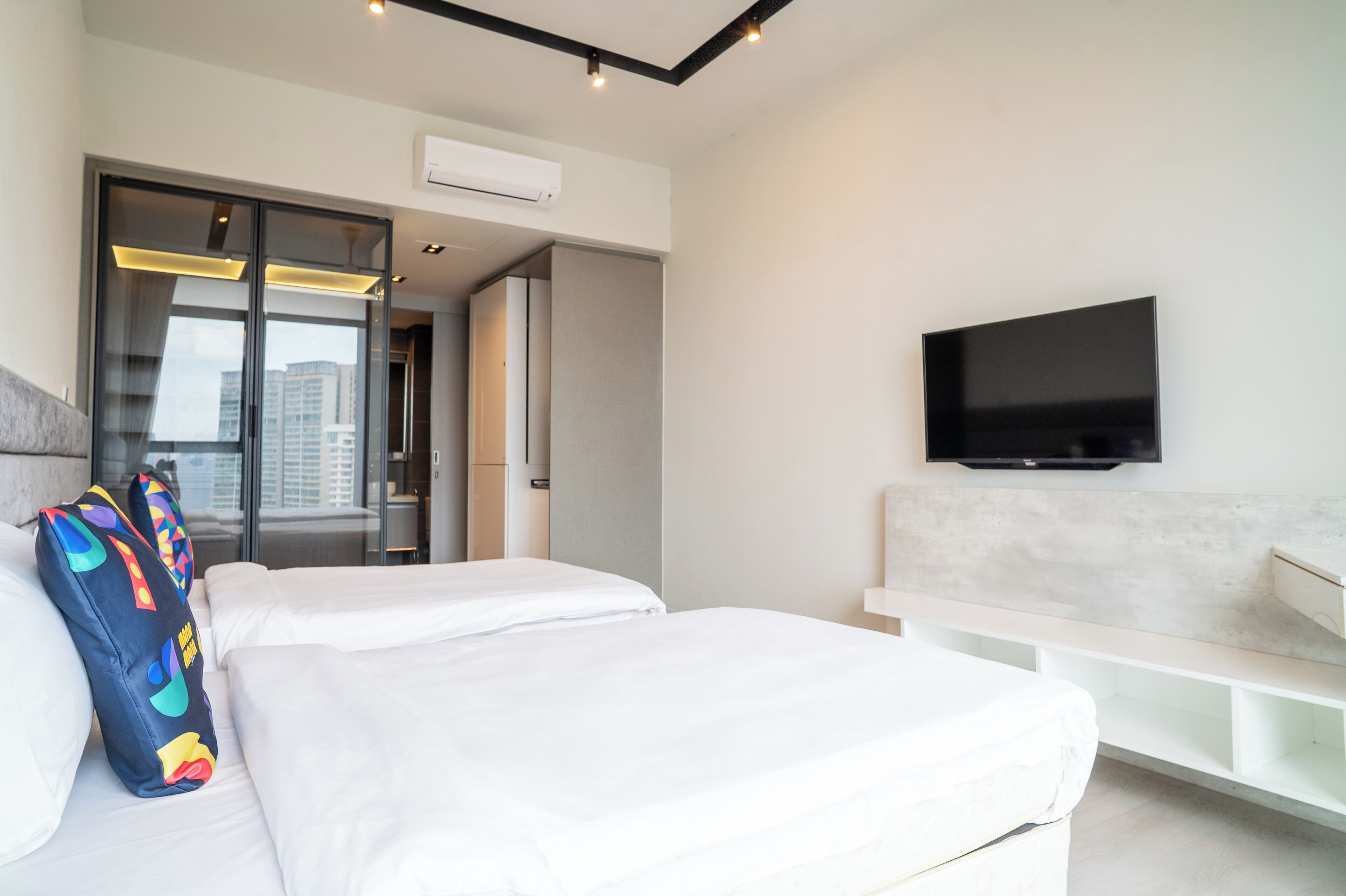Una habitación de hotel moderna con una cama grande, un televisor de pantalla plana montado en la pared y una puerta corrediza que da a un balcón.