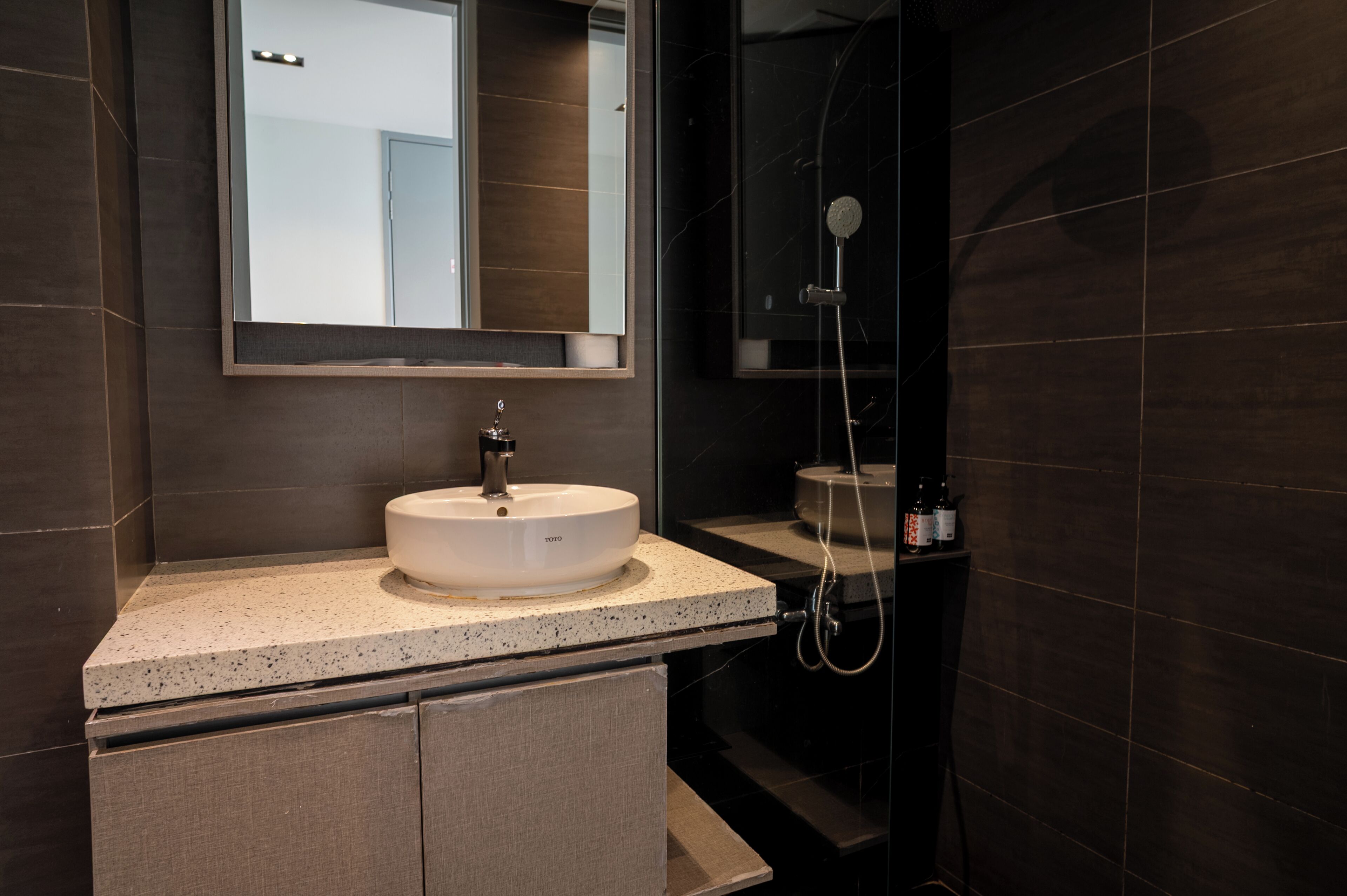 A modern bathroom with a round sink, a mirror above it, and a shower area.