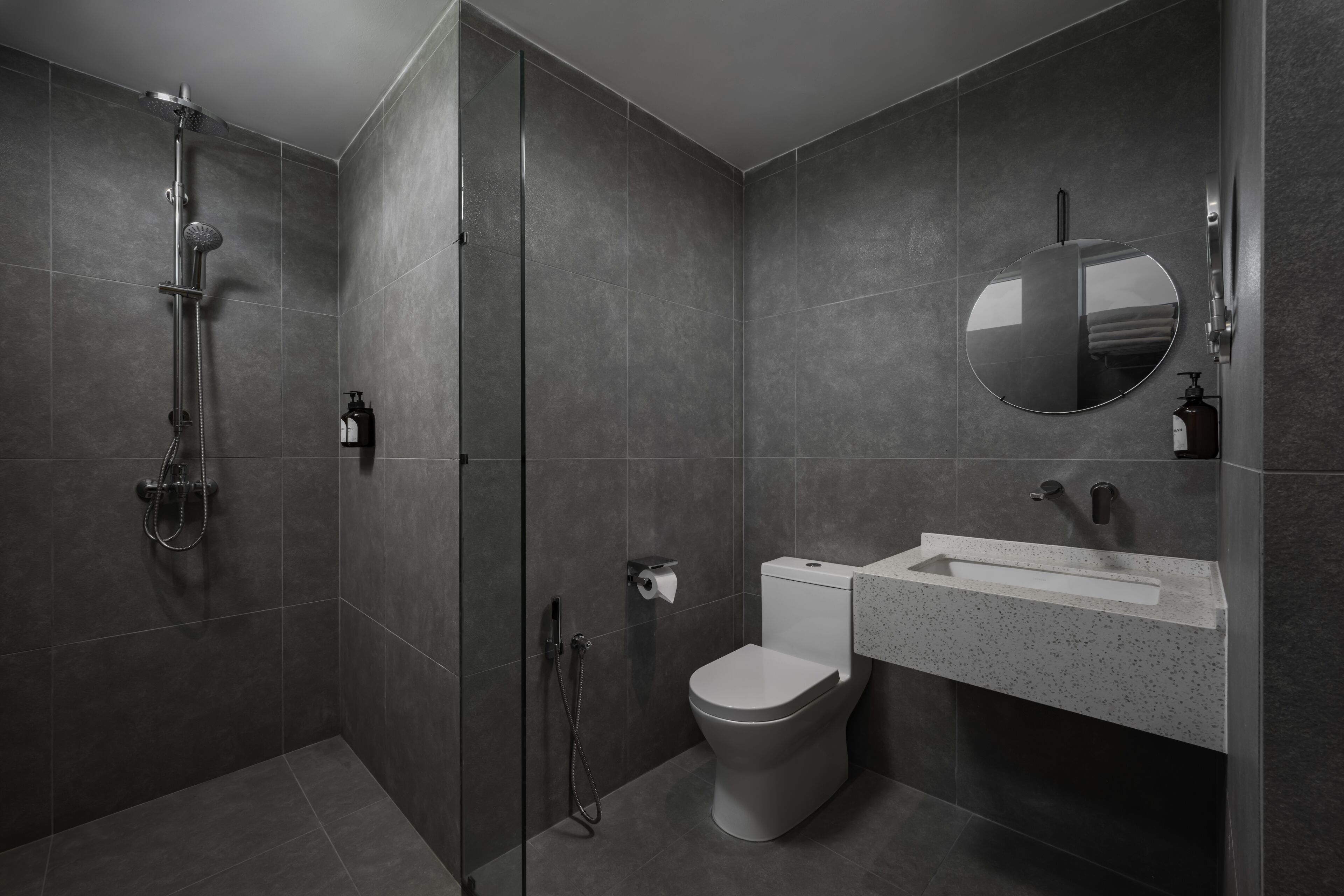 A modern bathroom with a glass-enclosed shower, a toilet, and a sink with a mirror.