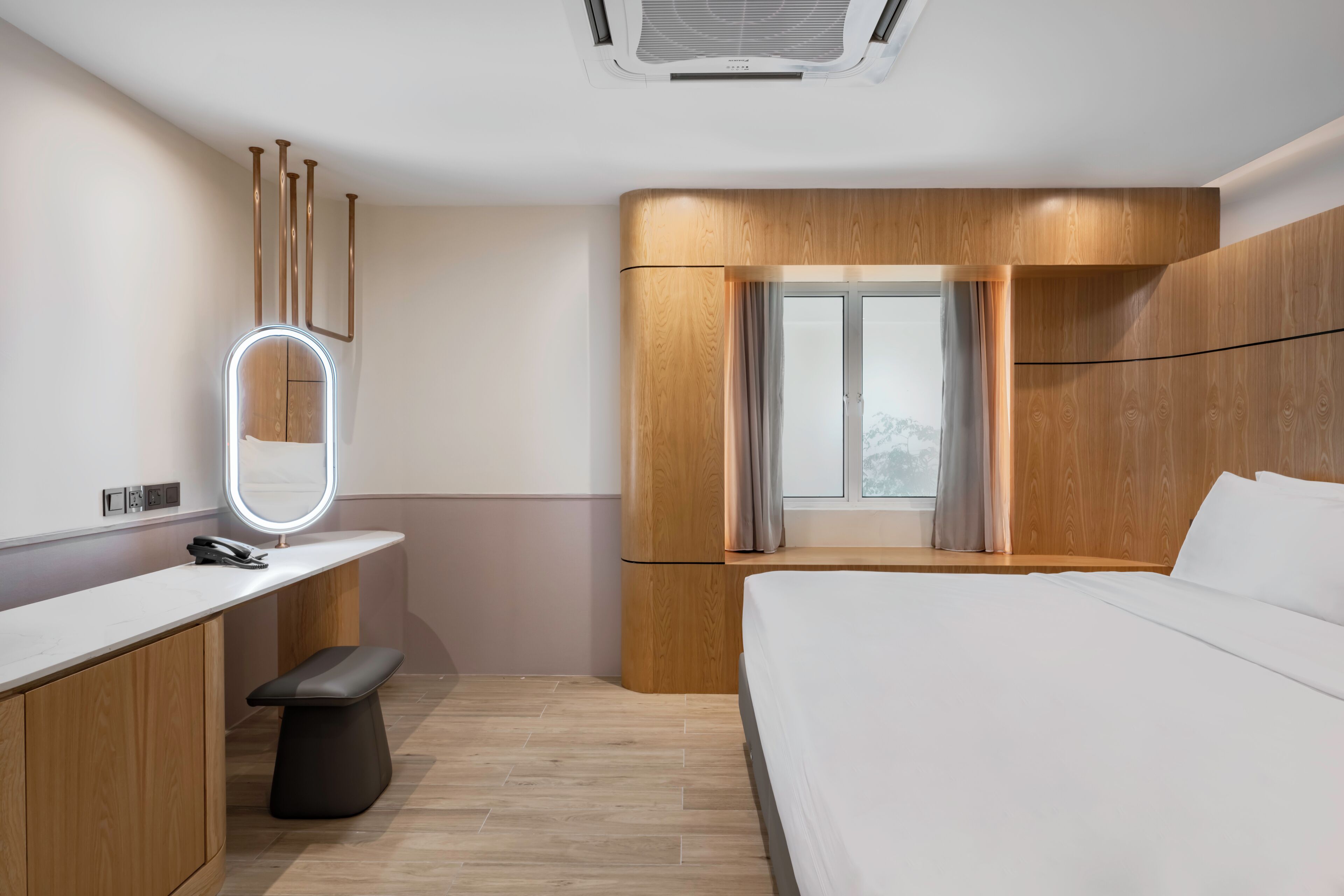 Une chambre d’hôtel moderne avec un mur d’accent en bois, un grand lit, une table de chevet avec un miroir et une fenêtre avec des rideaux.