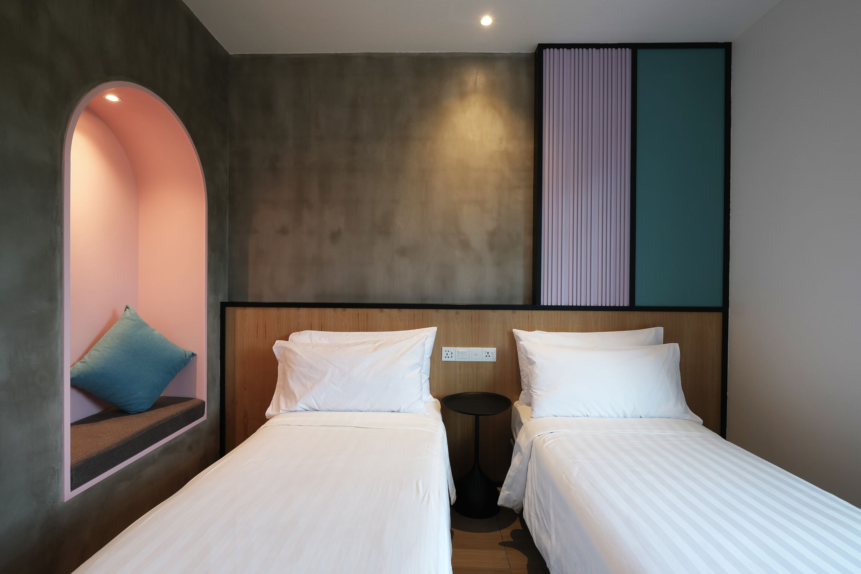 Hotelkamer met twee bedden, een tafeltje, een bank met kussen en een wandpaneel.
