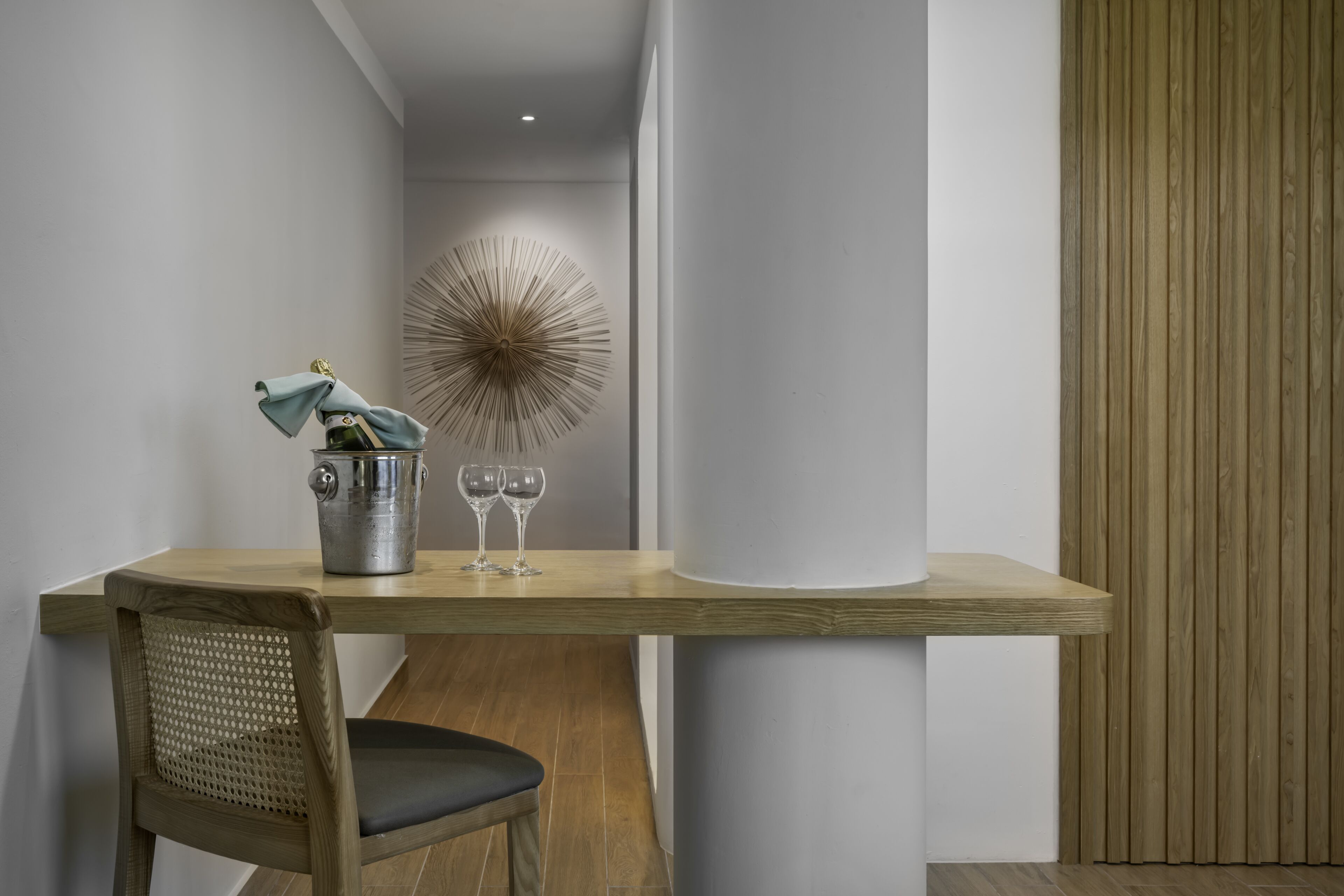 A modern dining area with a wooden table, a woven chair, and a decorative wall piece.