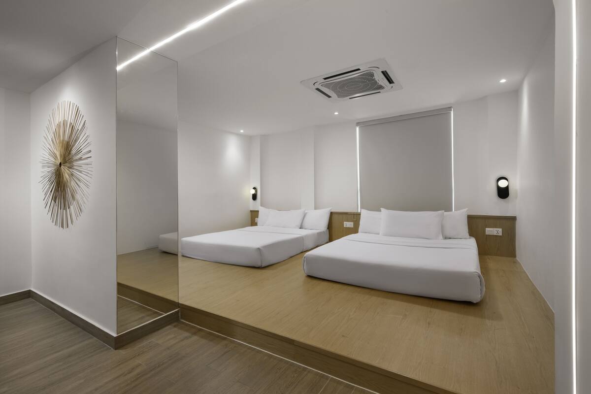 Une chambre d’hôtel moderne avec deux lits simples, un grand miroir et un élément décoratif mural.