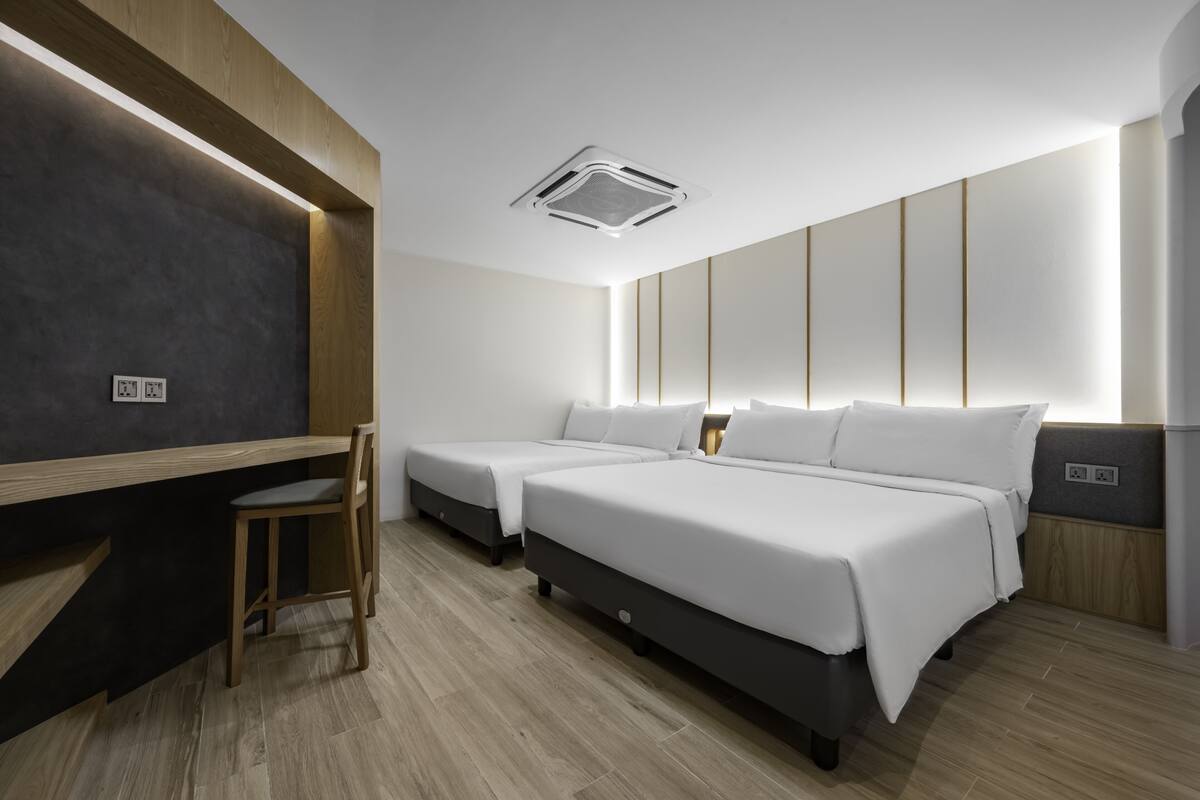 Une chambre d’hôtel moderne équipée de deux lits simples, d’un bureau et d’une chaise.