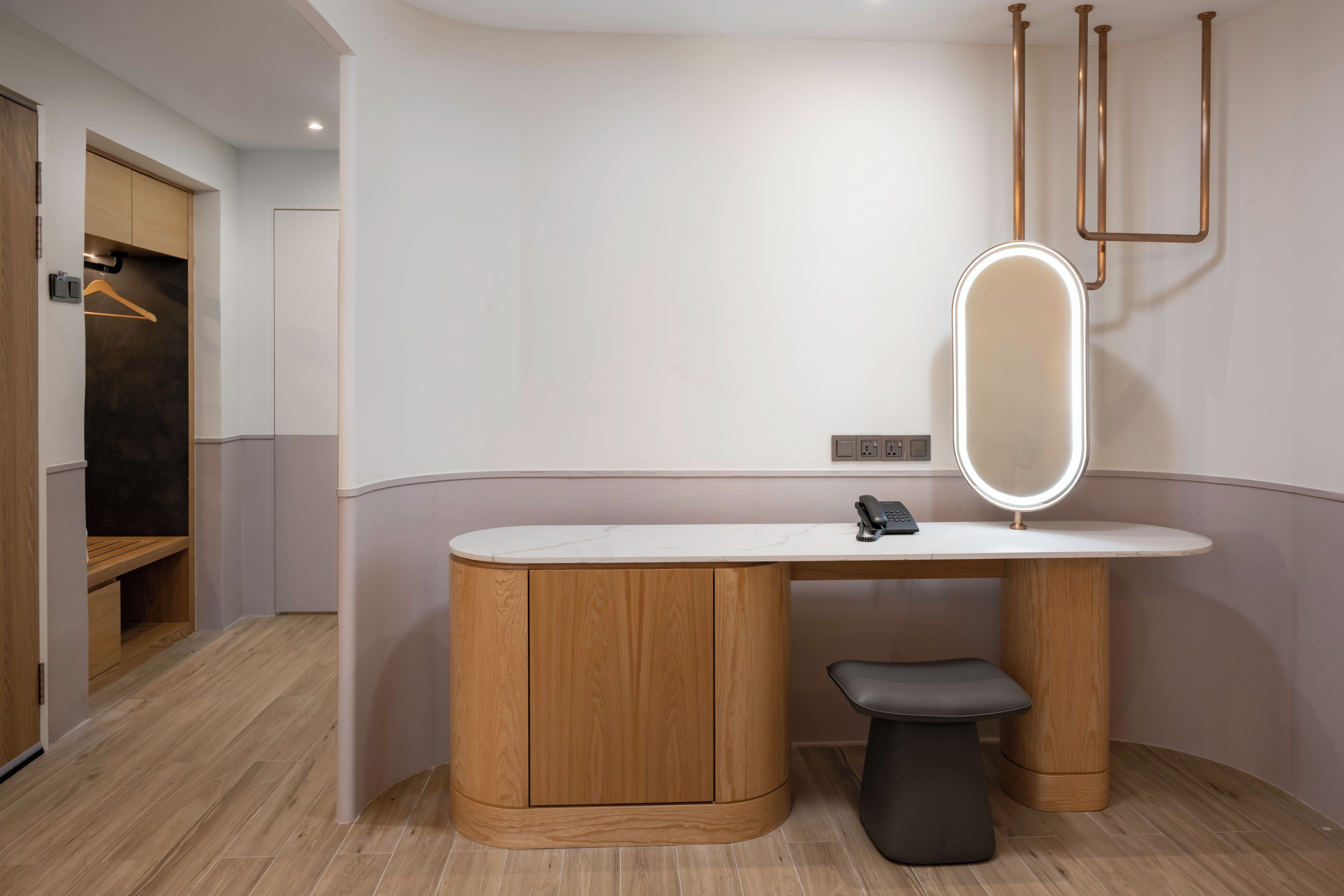 Une salle de bain moderne avec un meuble-lavabo en bois, un miroir rond avec un éclairage intégré et un banc.