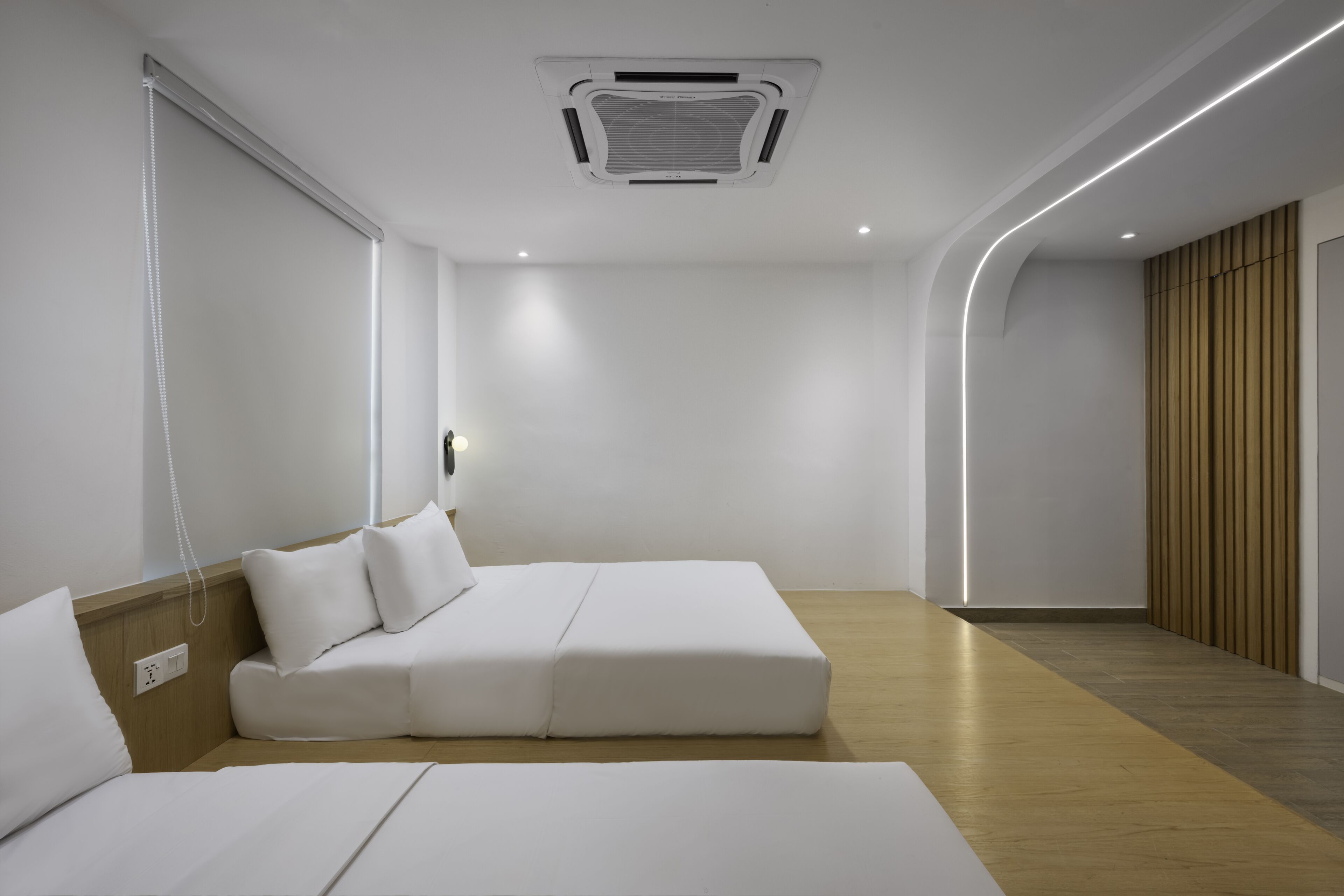 Una habitación de hotel moderna con diseño minimalista, que incluye una cama grande, una mesita de noche y un calefactor incorporado.