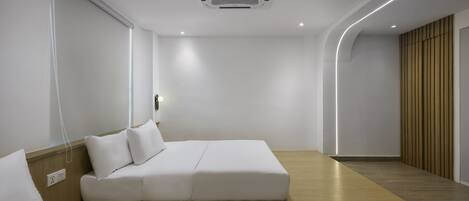 Una habitación de hotel moderna con diseño minimalista, que incluye una cama grande, una mesita de noche y un calefactor incorporado.