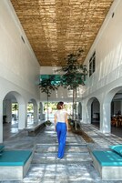 Un pasillo cubierto con techo de madera, paredes blancas y macetas verdes.