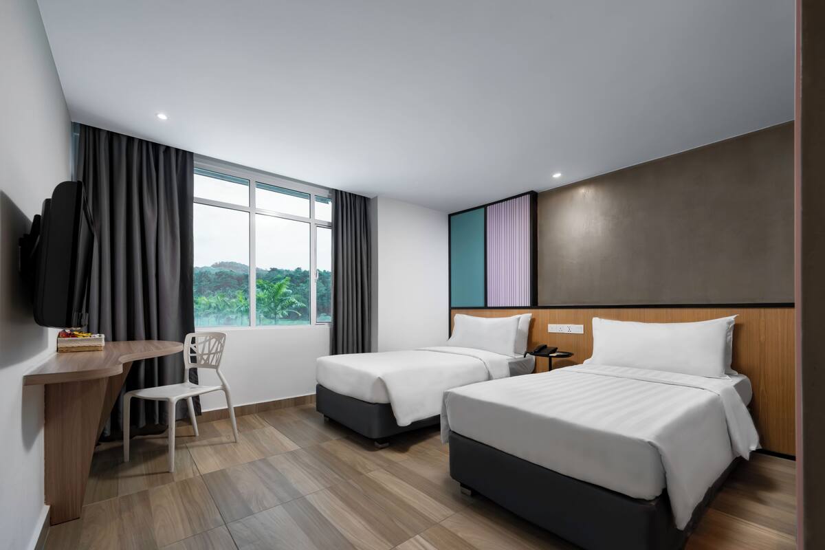 Une chambre d’hôtel moderne équipée de deux lits, d’un bureau, d’une chaise et d’un téléviseur.