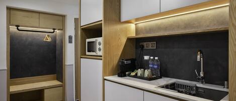 A compact kitchen with a microwave, sink, and storage cabinets.