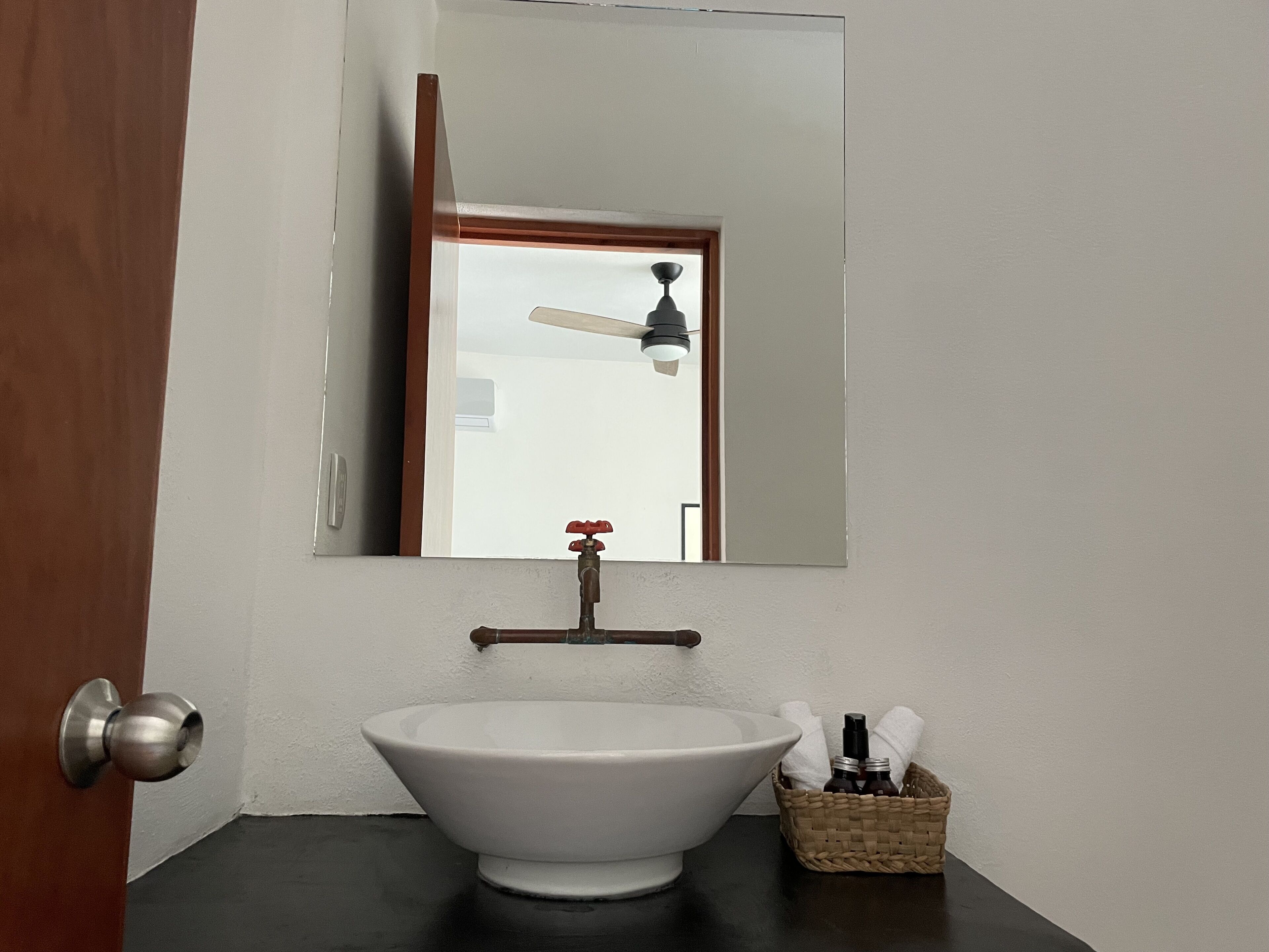 A bathroom with a white sink, a mirror above it, and a ceiling fan.