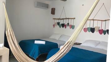 A room with two beds, a hammock, a ceiling fan, and a wall-mounted decoration.