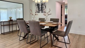 A modern dining area with a wooden table, grey upholstered chairs, and a unique spherical chandelier. - Newly Remodeled Beauty in Phoenix (Phoenix)