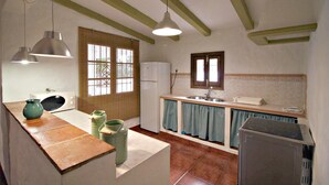 A kitchen with a refrigerator, stove, and hanging pendant lights. - Vacation Home 'El Rancho' with Mountain View, Pool, Wi-Fi & Garden (El Gastor)