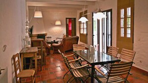A dining area with a table and chairs, a hanging light fixture, and a window with blinds. - Vacation Home 'El Rancho' with Mountain View, Pool, Wi-Fi & Garden (El Gastor)