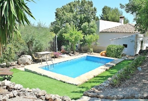 A rectangular swimming pool with a stone border, surrounded by a well-maintained lawn and various plants. - Holiday Home Casa Romántica with Mountain View, Pool & Wi-Fi (Ronda)