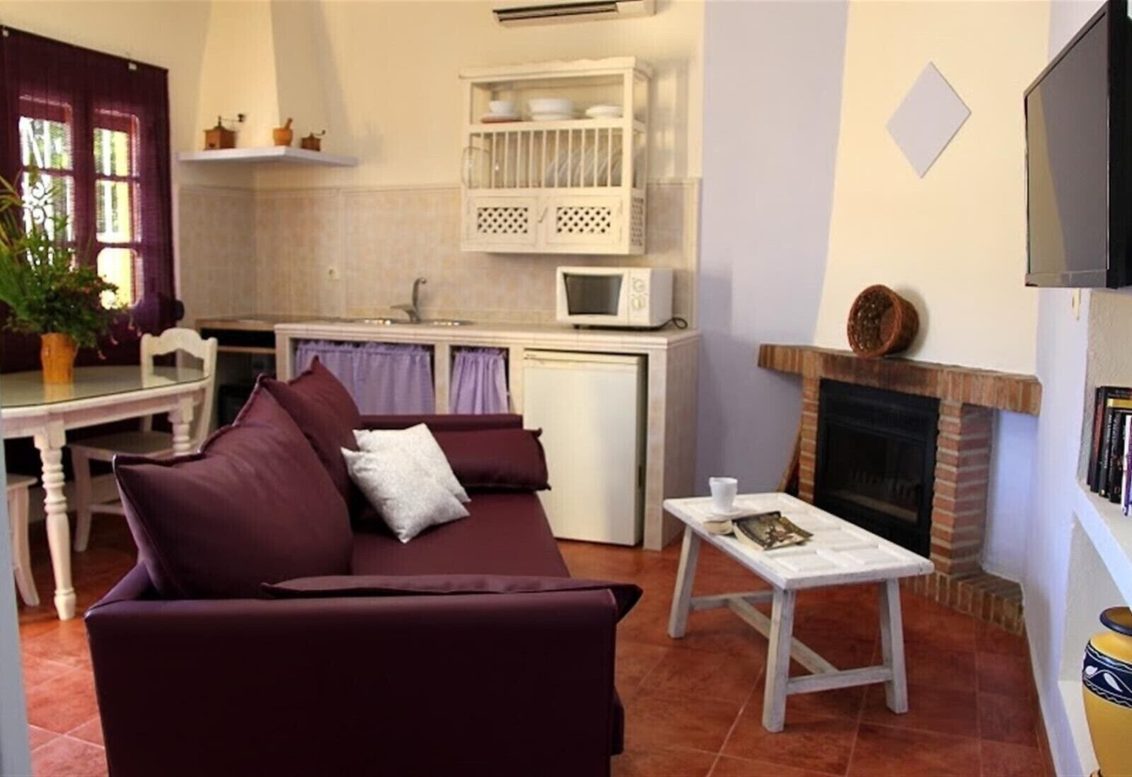 A compact living space with a sofa, a small table, a kitchenette, and a fireplace.