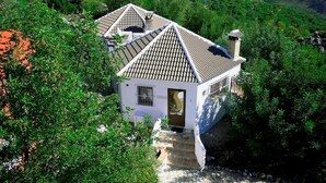 A white building with a tiled roof surrounded by greenery.