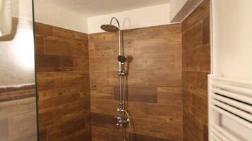 Une douche avec une porte en verre, des murs en bois et un radiateur blanc.