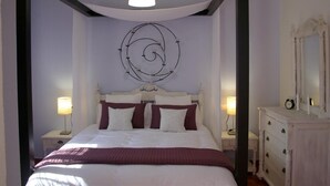 Une chambre à coucher comprenant un lit, des lampes de chevet, une commode et un luminaire fixé au mur.