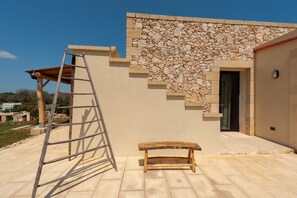 Un bâtiment avec une façade en pierre, un banc en bois et une échelle.