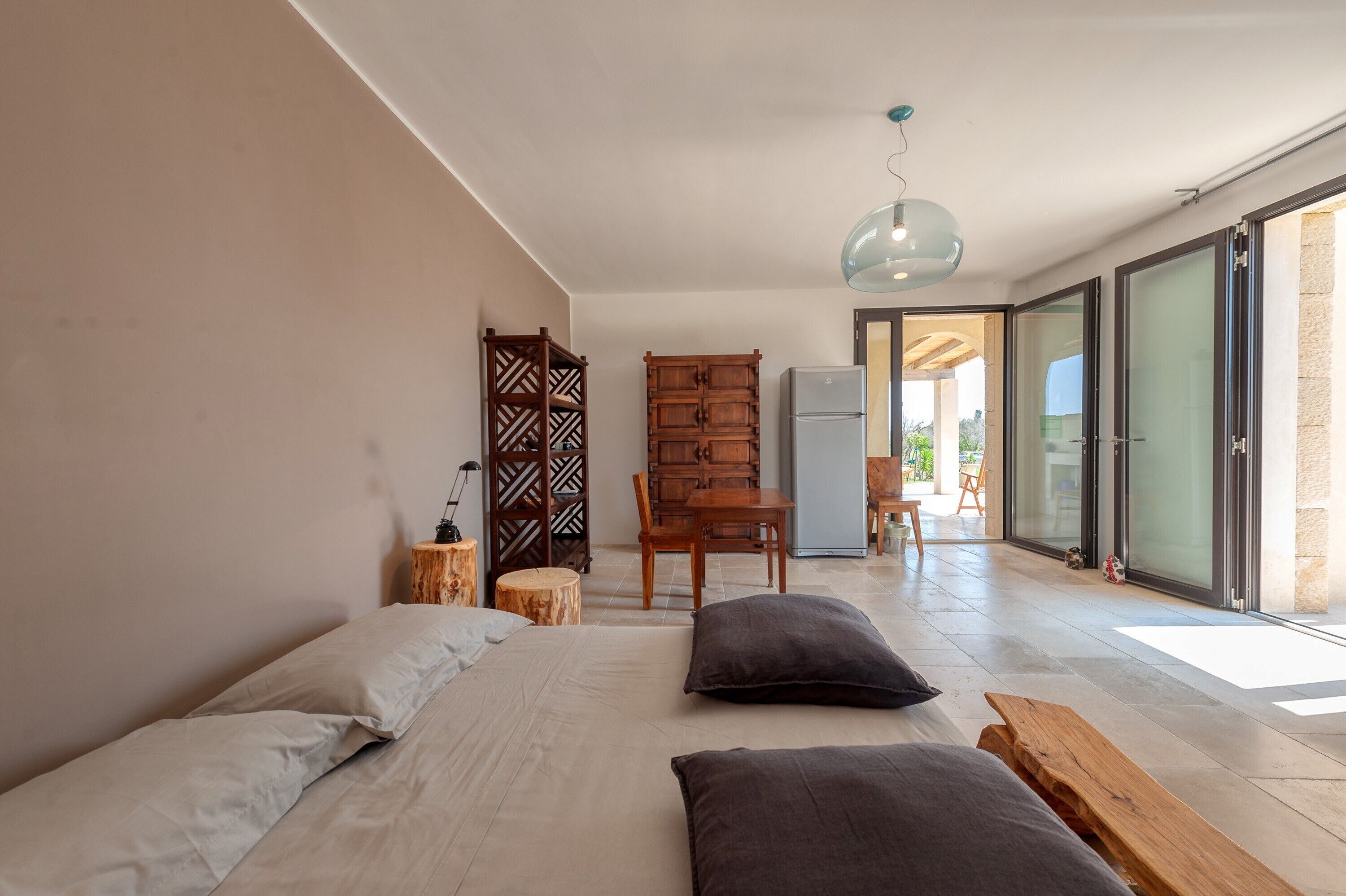 Ein Schlafzimmer mit einem Bett, Kissen, einer Holzbank, einem Schreibtisch und einem Stuhl.