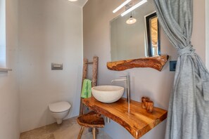 Une salle de bain avec un meuble-lavabo en bois, un lavabo blanc, des toilettes et un miroir.