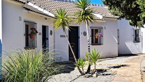 A white building with a tiled roof, a door, and windows with flower boxes. - 'Studio Romantic Paradise 3' with Mountain View, Pool, Wi-Fi & Garden (Ronda)