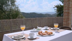 A table set for breakfast with croissants, orange juice, and a view of hills. - 'Studio Romantic Paradise 3' with Mountain View, Pool, Wi-Fi & Garden (Ronda)