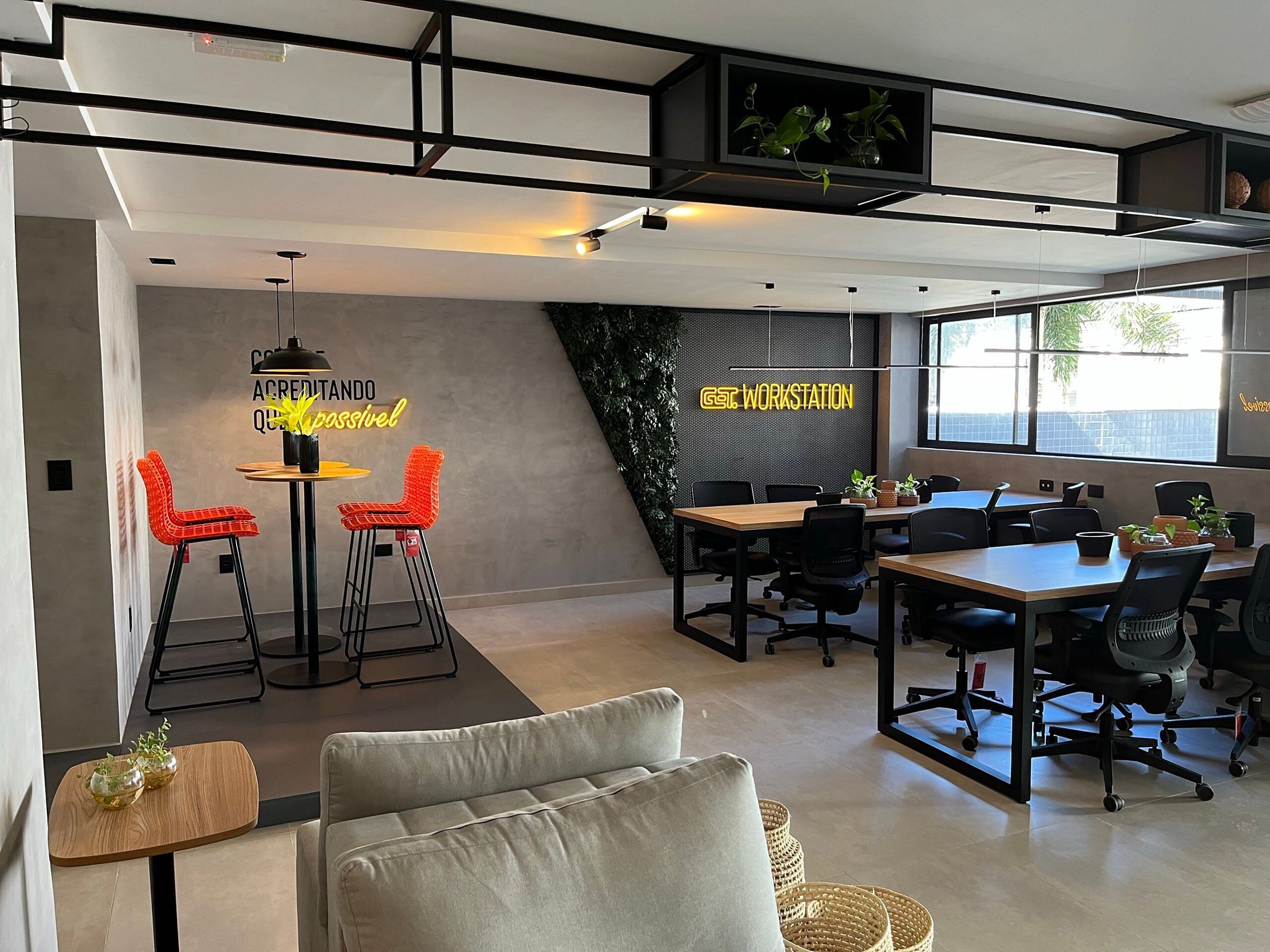 Un moderno spazio ufficio con un'area collaborativa che include un lungo tavolo, diverse sedie e un neon.