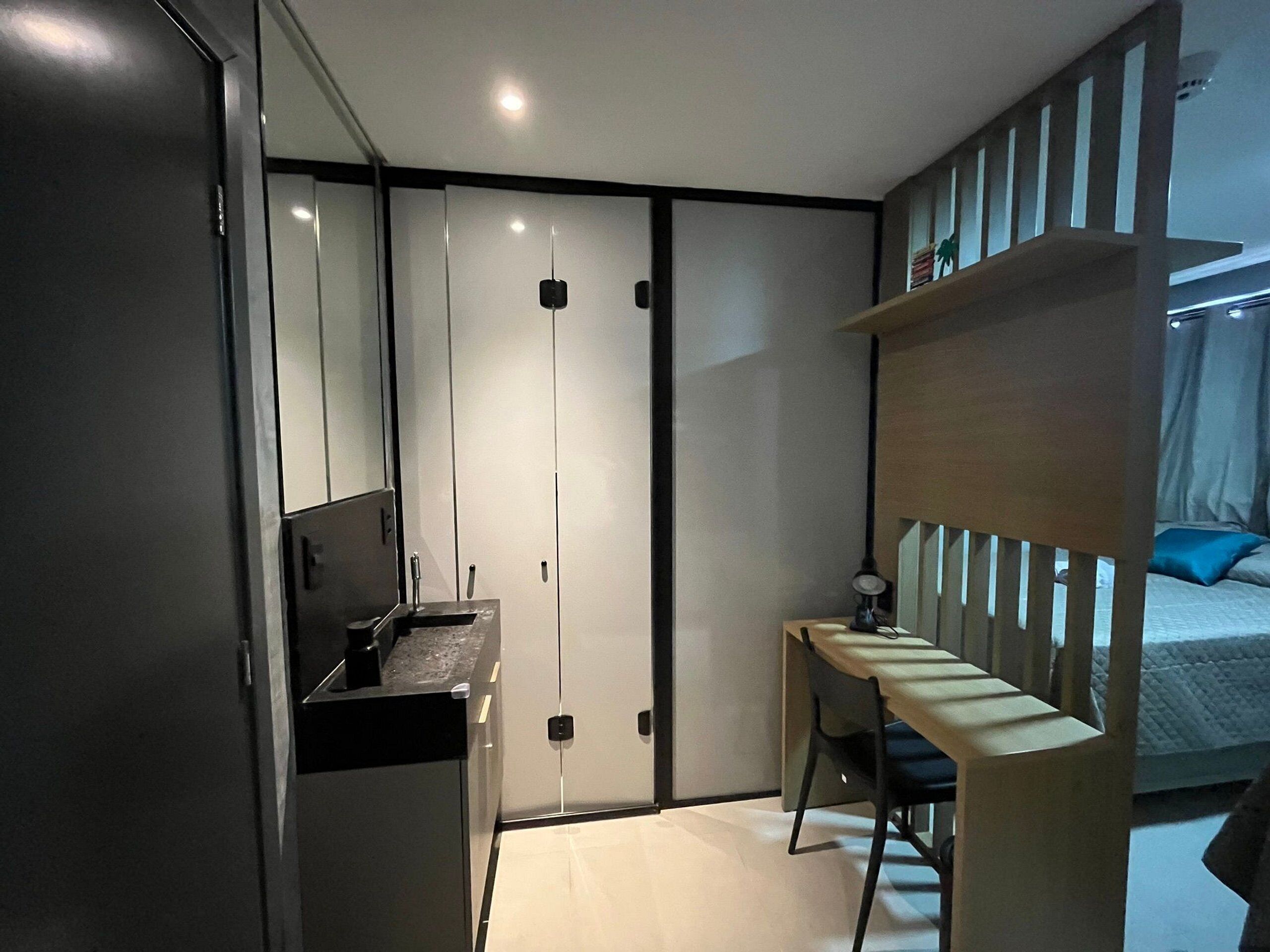 A modern bedroom with a bed, a desk, and a chair. There is a wardrobe with sliding doors and a mirror.