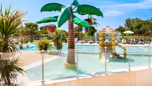 A pool area with a palm tree sculpture, lounge chairs, and a gazebo. - Mobil-Home Baia with Sea View and Private Terrace (Saint-Raphaël)