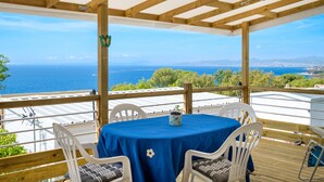 A covered outdoor seating area with a table and chairs, overlooking a scenic view of the sea and distant land. - Mobil-Home Baia with Sea View and Private Terrace (Saint-Raphaël)